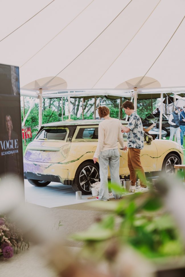 The half-painted MINI Art Car under a white canvas tent in the Vogue Scandinavia lounge at The Aurora, with Robert and Madelen Möllard working beside it