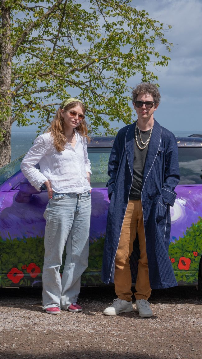 Robert Möllard in a navy robe and pearl necklace standing with Madelen Möllard in front of the finished MINI Art Car